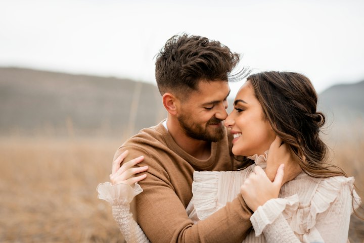 Una pareja abrazada y sonriendo en un campo